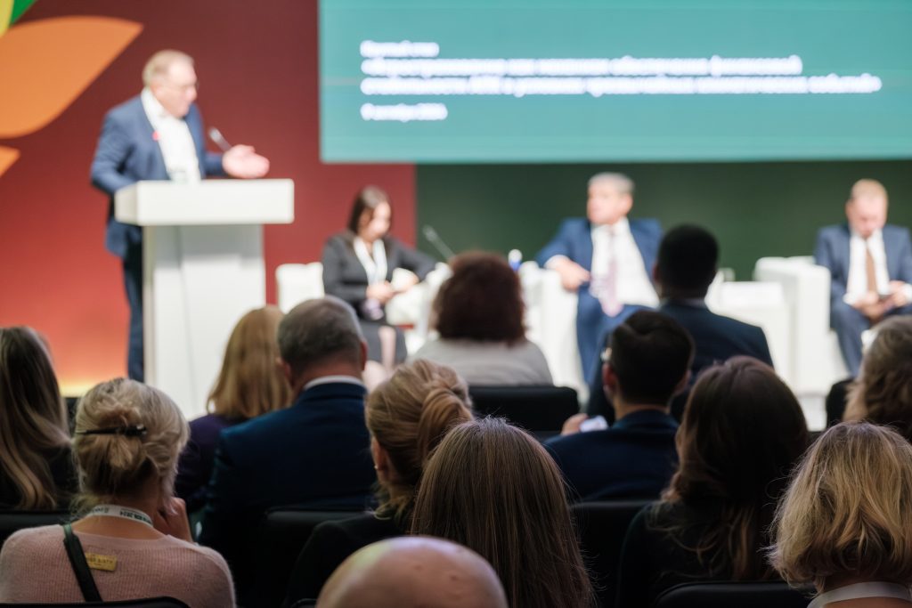 Business conference featuring panel discussion with professionals and audience interaction at modern event venue under dim lighting. By Anton Gvozdiko