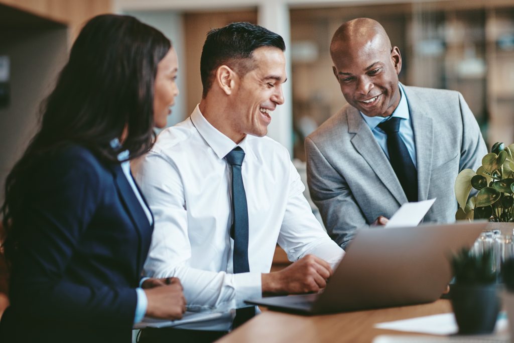 Diverse businesspeople laughing while working together at an office By Flamingo Images