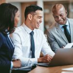 Diverse businesspeople laughing while working together at an office By Flamingo Images